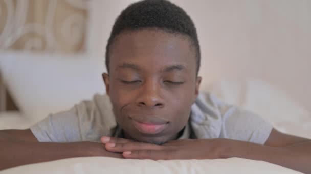 Молодой Африканский Человек Лежит Постели Животе Улыбается Камеру — стоковое видео