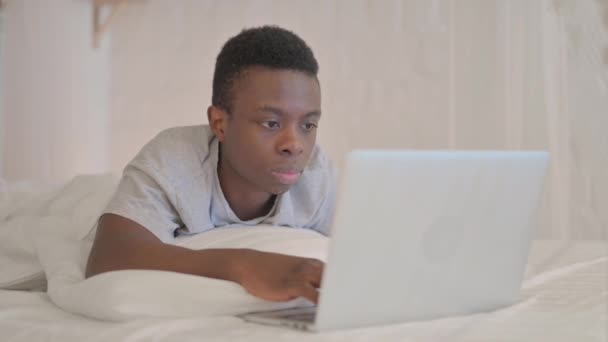 Poważny Młody Afrykanin Leżący Łóżku Brzuchu Patrząc Aparacie — Wideo stockowe