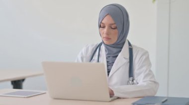 Klinikte dizüstü bilgisayarda çalışan Müslüman kadın doktor