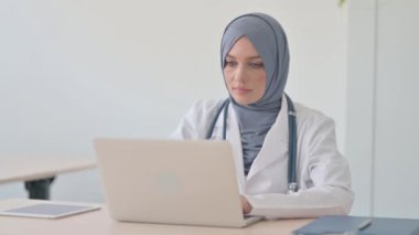 Bilgisayarda çalışan Müslüman Kadın Doktor Kameraya doğru bakıyor