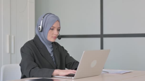 ヘッドセットを持つイスラム教徒のビジネス女性ノートパソコンで作業 — ストック動画