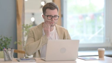 Genç İşadamı dizüstü bilgisayar ve enfeksiyon üzerinde çalışırken diş ağrısı çekiyor.