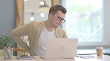 Young Businessman with Back Pain Working on Laptop