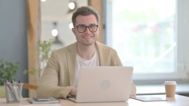 Genç İşadamı Bilgisayarda Çalışırken Kameraya Gülümsüyor