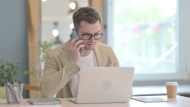 Kızgın genç adam telefonda tartışıyor.