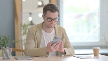 İş yerinde akıllı telefon kullanan genç bir iş adamı.