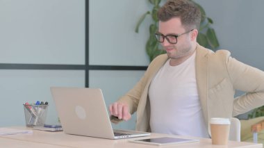 Young Businessman with Back Pain Working on Laptop