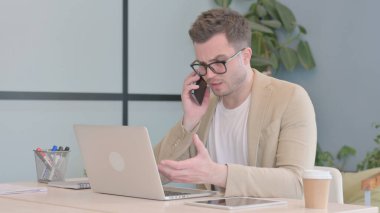 Kızgın genç adam telefonda tartışıyor.