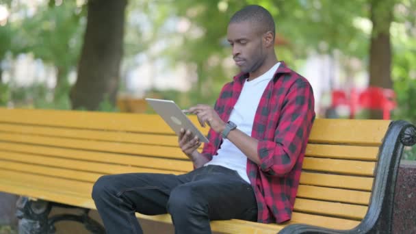Joven Africano Celebrando Éxito Tableta Mientras Está Sentado Aire Libre — Vídeo de stock