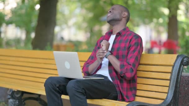 在室外笔记本电脑上工作的有愤怒之痛的非洲年轻人 — 图库视频影像