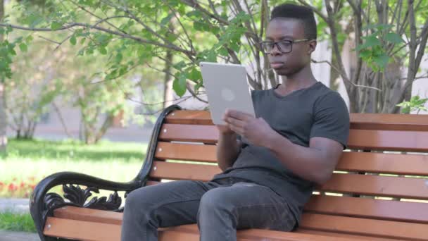 Pemuda Afrika Merayakan Sukses Tablet Sambil Duduk Outdoor Pada Bench — Stok Video