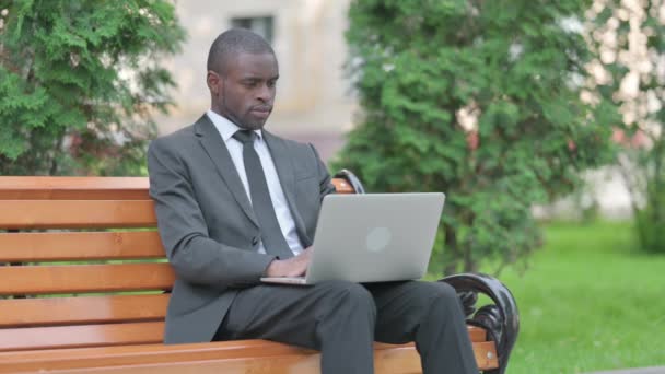 屋外に座っている間にラップトップを使用してアフリカのビジネスマン — ストック動画