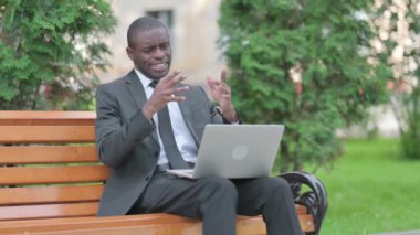 Diz üstü bilgisayar kullanırken gergin hisseden endişeli Afrikalı iş adamı
