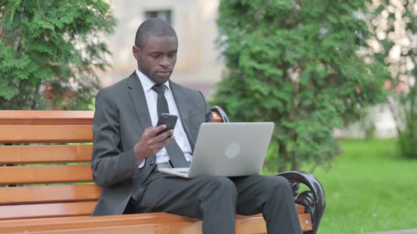 在笔记本电脑和智能手机上工作的非洲商人 — 图库视频影像