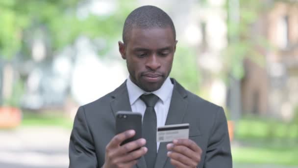 Захоплений Африканський Бізнесмен Покупки Онлайн Телефону Сидячи Відкритому Повітрі Лавці — стокове відео