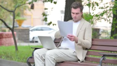 Gündelik Genç Adam Laptop ve Dokümanlar üzerinde çalışırken kutlama yapıyor