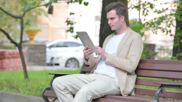 Nenucený Mladý Muž Slaví Úspěch Tabletu Zatímco Sedí Venku Lavičce — Stock video