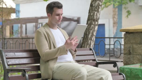 Joven Molesto Por Pérdida Tableta Mientras Está Sentado Aire Libre — Vídeos de Stock