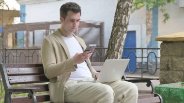 Laptop ve Smartphone 'da çalışan genç adam