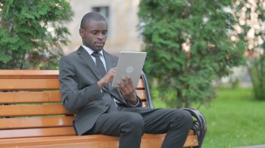 Bir bankta otururken Tablet kullanan Afrikalı İşadamı