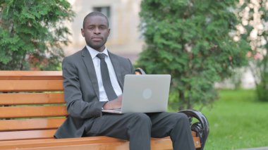 Disaridaki Laptop 'ta calisirken kameraya bakan Afrikalı is adami