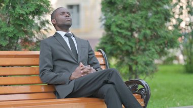 Afrikalı İşadamı geliyor, bankta oturuyor.