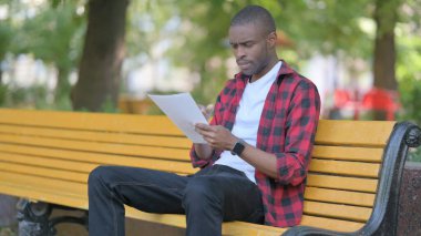 Genç Afrikalı Adam Dışarıda Otururken Belgeleri Okurken