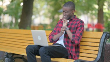 Dizüstü bilgisayarda çalışan bilek ağrısı olan genç Afrikalı adam.