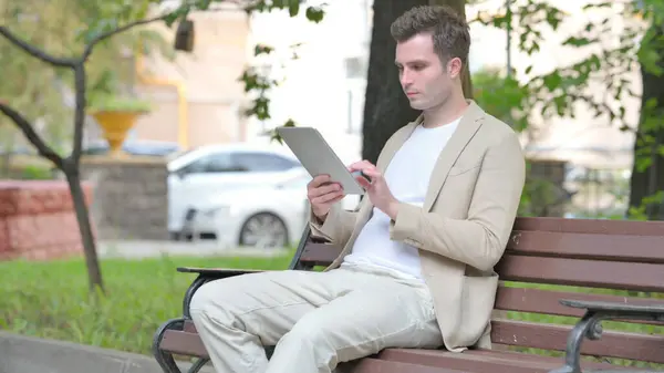Casual Young Man Using Tablet While Sitting Outdoor Bench — Stock Photo, Image