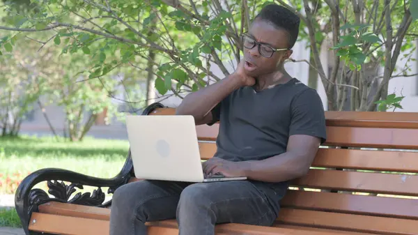 Young African Man with Neck Pain Working on Laptop Outdoor