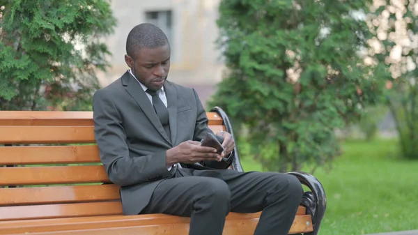 African Businessman With Empty Purse Sitting Outdoor, No Money
