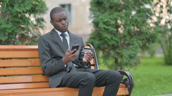 African Businessman Upset by Online Payment Failure on Phone Outdoor