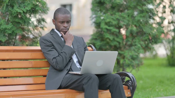 African Businessman Thinking and Working on Laptop Outdoor