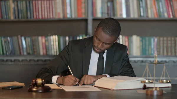 Pensive African Male Lawyer Writing Legal Documents in Office