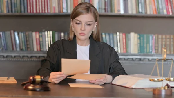 Young Female Lawyer Reading Legal Documents in Office