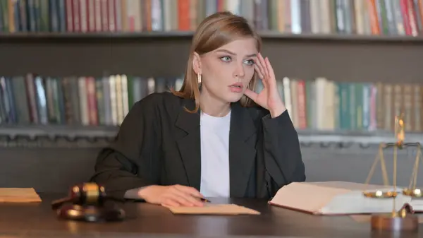 Upset Young Female Lawyer Reading Law Book in Office