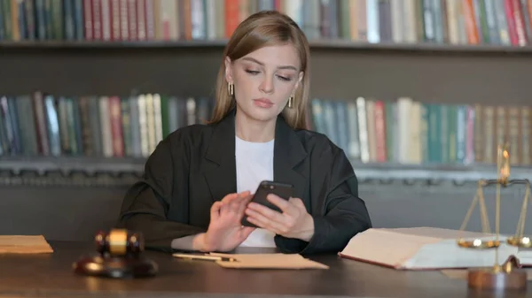 Young Female Lawyer Browsing Internet on Phone in Office