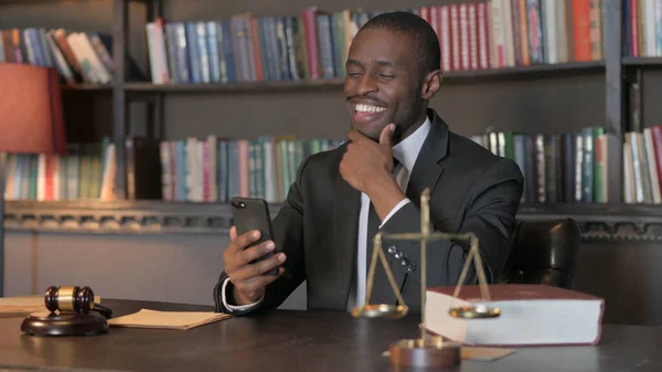 African American Lawyer Celebrating Win on Smartphone in Office