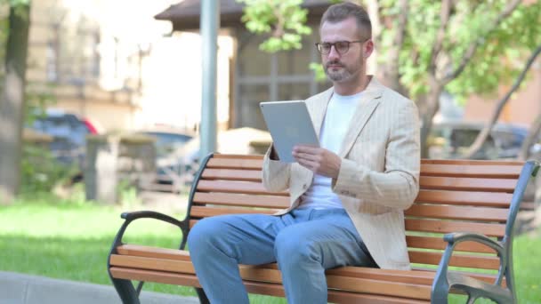 Middle Aged Man Using Tablet While Sitting Outdoor Bench — Stock Video