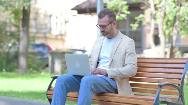 Homem Meia Idade Apontando Para Câmera Enquanto Usa Laptop Livre — Vídeo de Stock