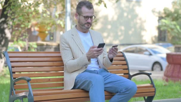 Сучасний Випадковий Чоловік Робить Інтернет Покупки Телефону Сидячи Відкритому Повітрі — стокове відео