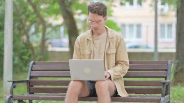 Laptop kullanan sıradan bir genç adam öksürüyor.