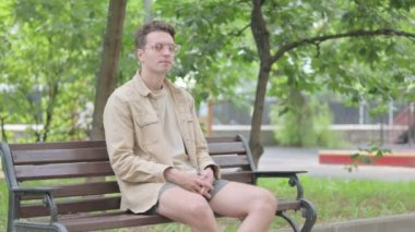 Boyun ağrısı olan modern genç adam Bench 'te oturuyor.