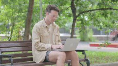 Başağrısı olan modern genç adam Laptop 'u açık havada kullanıyor
