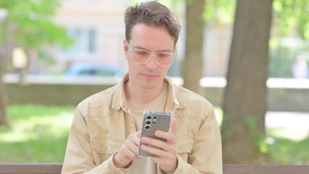 Zdenerwowany Przypadkowy Młody Człowiek Wstrząśnięty Smartfon Odkryty — Wideo stockowe