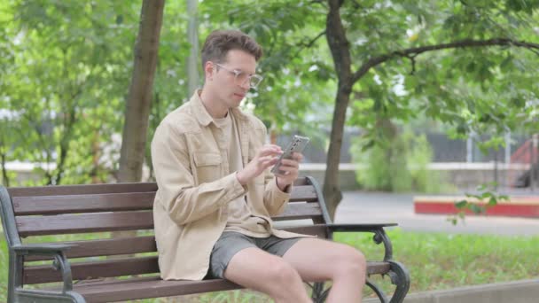 Modern Young Man Facing Loss Smartfonie Siedząc Ławce — Wideo stockowe