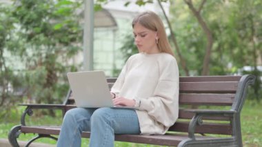 Baş ağrısı olan sıradan bir genç kadın laptopla dışarıda çalışıyor.