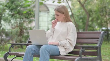 Laptop kullanan sıradan bir genç kadın öksürüyor.