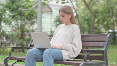 Dizüstü bilgisayarla çalıştıktan sonra sıradan bir genç kadın Bench 'i açık havada terk ediyor.