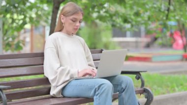 Dizüstü bilgisayarla çalıştıktan sonra Bench 'i açık havada bırakan genç kadın.